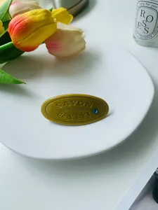 Vue détaillée d'une pince à cheveux jaune en forme de savon avec cristal bleu sur plat en porcelaine