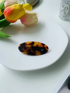 Détail d'une pince à cheveux écaille de tortue avec strass bleu sur une assiette en céramique
