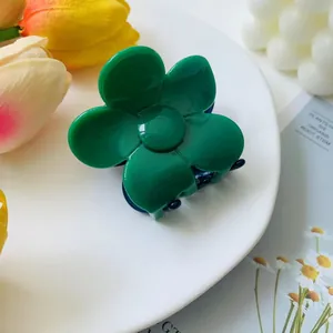 Detailed view of a bright green flower-shaped hair claw clip on a white ceramic tray