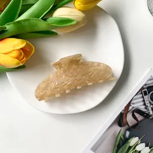 Détail d'une grande pince à cheveux crème en acétate avec texture coquillage sur assiette