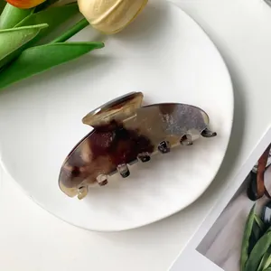 Détail d'une pince à cheveux en acétate écaille de tortue sur une assiette blanche