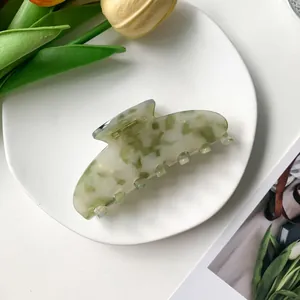 Détail d'une pince à cheveux de 9cm à motif marbré vert et blanc avec décor floral