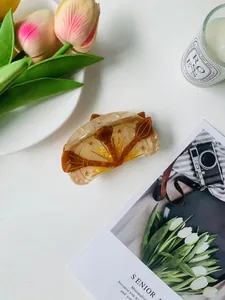 Detail of acetate shark hair claw with golden broom and star patterns in amber texture