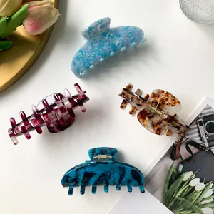 Set of four 9cm acetate hair claws in various marble patterns on white background