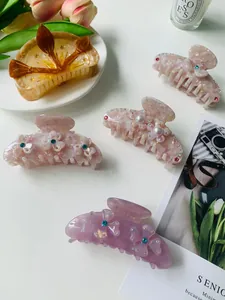 Detailed close-up of acetate hair claws with marble patterns, pearls, and rhinestones