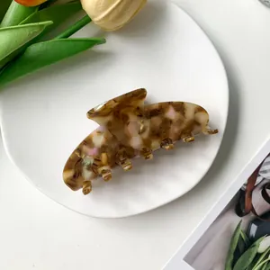 Gros plan d'une pince à cheveux en acétate écaille de tortue sur une assiette blanche épurée