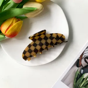 Detailed view of a 9cm acetate checkerboard hair claw clip on a white decorative plate