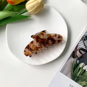 Macro shot of 9cm tortoise shell acetate hair claw clip on white ceramic tray
