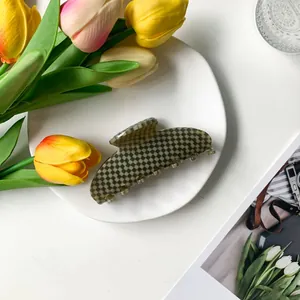 Detail of 9cm acetate hair claw with olive and khaki checkerboard pattern on a white dish