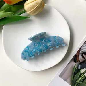 Detailed top view of 9cm blue marble acetate hair claw clip on elegant white ceramic plate