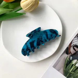 Detailed close-up of blue marble acetate hair claw clip on a stylish lifestyle background
