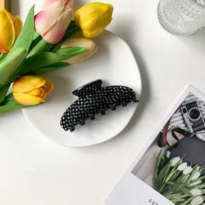 Macro detail of a 9cm checkerboard acetate hair claw clip on an elegant table setting