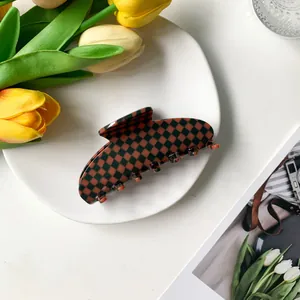 Detail of 9cm acetate hair claw with orange and black checkerboard pattern on white plate