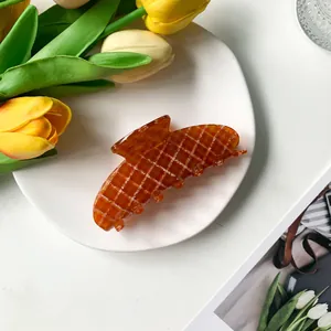 Detail of 9cm acetate hair claw with amber tones and white checkered pattern on a plate