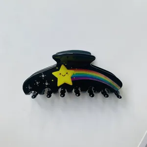 Dettaglio molletta per capelli nera con motivo stella arcobaleno e strass luminosi