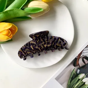Primer plano de pinza de pelo de acetato con estampado de leopardo morado y pan de oro