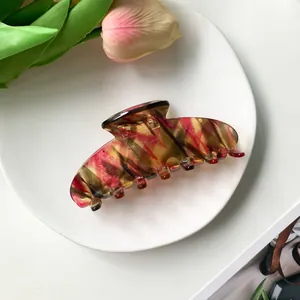 Detail shot of a large marble hair claw clip with red and yellow acetate texture