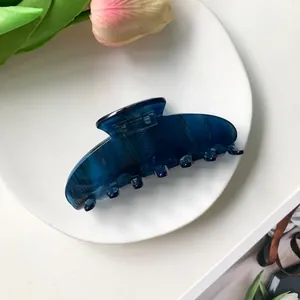 Macro view of blue marble acetate hair claw clip on a white ceramic plate with tulips