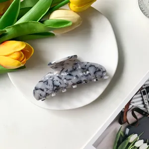 Detalle de una elegante pinza de pelo de acetato con textura de patrón de mármol blanco y negro