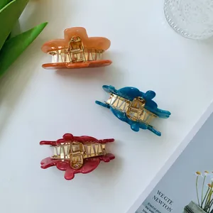 Three colorful irregular acetate hair claws on a white desk with lifestyle decor