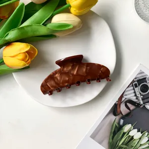 Detailed view of an amber tortoiseshell hair claw clip with a polished finish and sleek arc