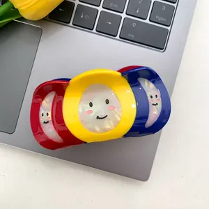 Detalle de pinza de pelo tricolor grande con carita sonriente sobre un portátil