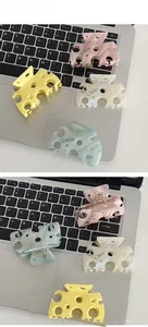 Détail des pinces à cheveux en acétate en forme de fromage en quatre couleurs pastel sur clavier