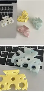 Gros plan de pinces à cheveux en acétate en forme de fromage aux tons pastel et logo