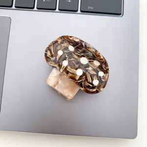 Detail der Pilz-Haarklammer mit bernsteinfarbener Marmorierung und weißen Punkten auf Laptop