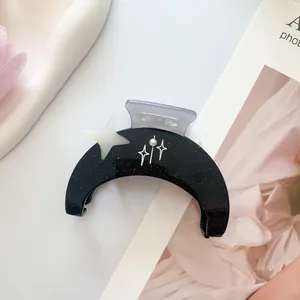 Detalle de pinza para el pelo negra en forma de luna con purpurina y acento de estrella perla