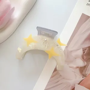 Detalle de pinza de pelo luna con estrellas amarillas, perlas y strass en base crema