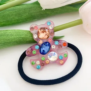 Dettaglio macro di un elastico per capelli a forma di orso rosa con strass colorati