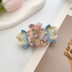 Detail view of a luxury candy-shaped acetate hair claw clip with rhinestones and floral texture