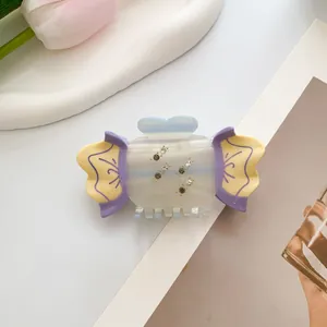 Detail of candy-shaped claw clip with rhinestones in pastel purple and yellow acetate
