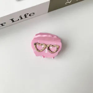 Detailed close-up of pink hair claw clip featuring heart-shaped gold eyeglasses pattern