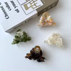 Set of four elegant acetate bow hair claws in marble, tortoiseshell, and cream colors