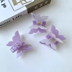 Drei Lavendel Schmetterling Haarklammern aus Acetat auf einem ästhetischen weißen Tisch