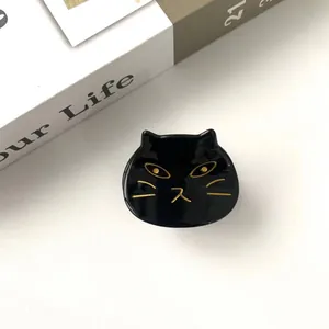 Detailed view of black cat hair claw clip with golden facial details on smooth surface