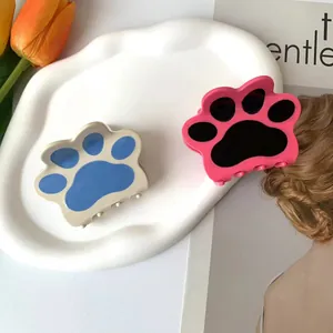 Lindas pinzas para el cabello con forma de pata de gato en una bandeja de cerámica