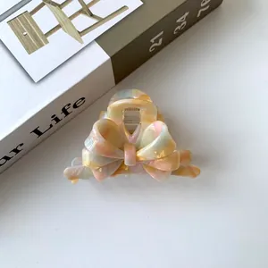 Detailed macro of a French marble acetate bow hair claw clip with colorful resin patterns