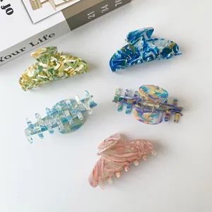 Five assorted marble patterned acetate hair claws in various colors on a white background