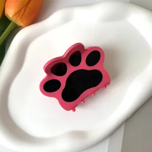 Pinza para el pelo con diseño de garra de gato rosa y negra sobre bandeja blanca