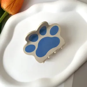 Detalle de la pinza para el cabello con garra de gato en beige y azul sobre bandeja