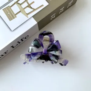 Detailed view of French-style acetate hair claw clip with purple marble bow design