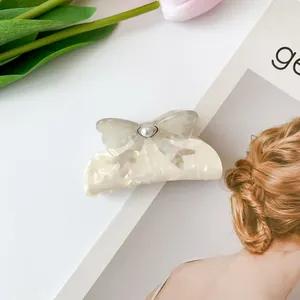 Nahaufnahme der cremefarbenen Haarklammer mit grauer Schleife, Perle und Tulpenhintergrund