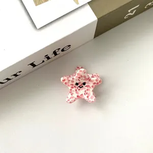 Gros plan d'une pince à cheveux étoile de mer rose à pois avec un visage souriant