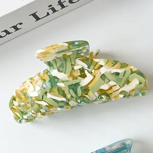 Detail of large acetate hair claw clip showing green and white marble texture