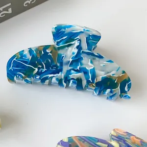Detailed view of the marbled blue and gold acetate hair claw clip on white background