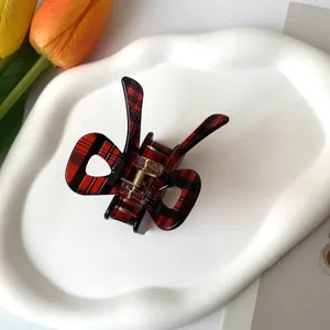 Détail d'une pince à cheveux en acétate à carreaux rouge et noir avec ressort doré