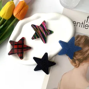 Set of four star-shaped acetate hair clips with plaid and glitter patterns on a ceramic tray